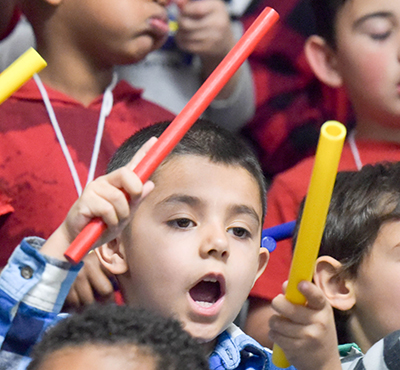 kid banging sticks and singing