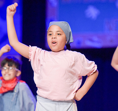 girl in scarf on stage with hand in air