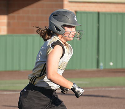 girl with batting helmet running to first base