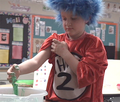 kid in thing 1 outfit with green gak on hand