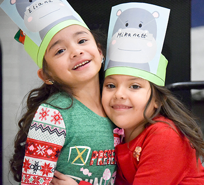 two girls in hippo hats hugging