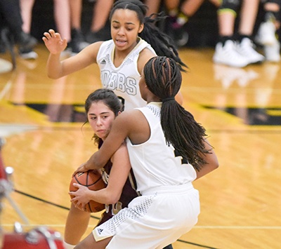 two players smothering another on defense