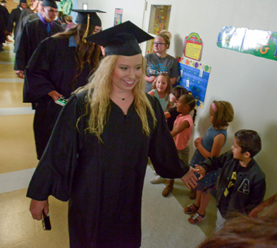 girl in cap and gown walking down hallway