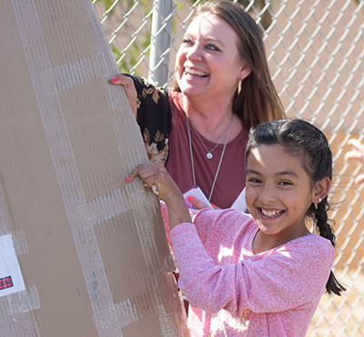 teacher and student unveiling sign and smiling