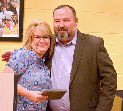 woman with plaque being hugged by man