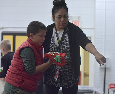 kid holding stocking and teacher pointing