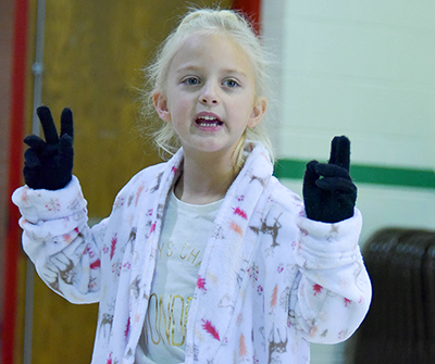 girl in pajamas holding up gloved  fingers