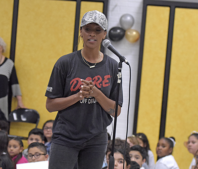 woman standing at microphone talking to students