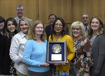 smiling people in line holding plaque