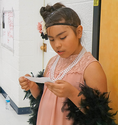 girl in costume reading from note card