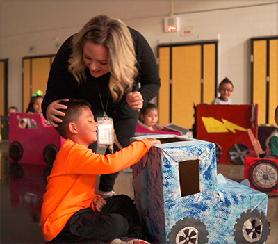 teacher with student in front of homemade car