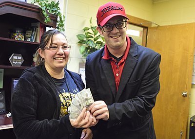 two smiling people holding $500