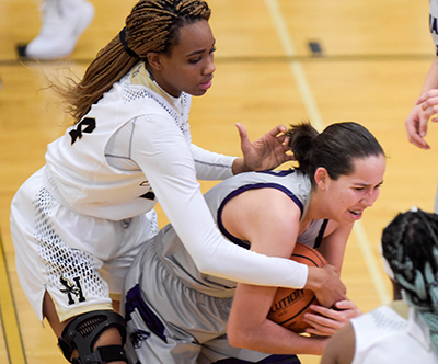 girl trying to hold onto ball while lady eagle player reaches for it