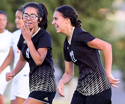 two girls laughing after scoring