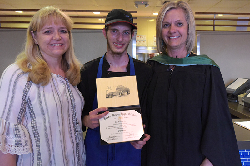 guy in uniform with diploma with 2 school administrators