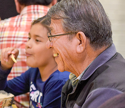 grandpa smiling while eating with granddaughter