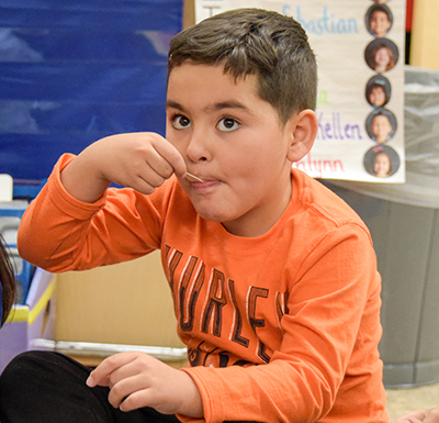 boy with ice cream spoon in mouth