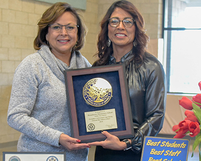 two woman standing with a plaque