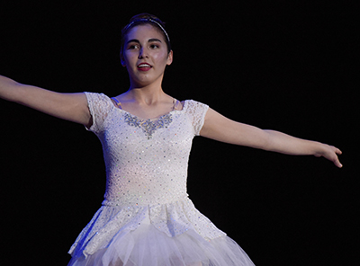 girl in white ballet outfit with arm extended