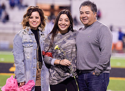 parents hugging daughter who is holding flower