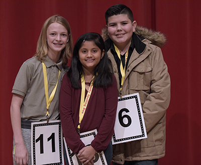 three students with numbers standing on stage