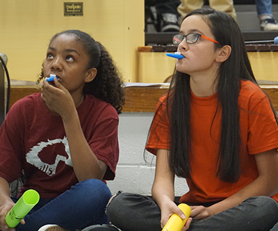 two students sitting with gazoos in mouth