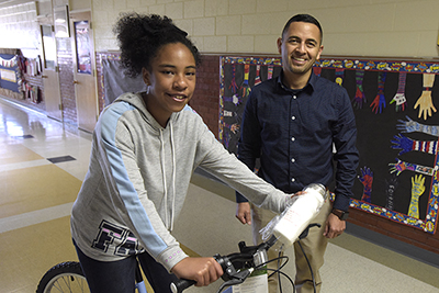 girl sitting on bike while man stands behind her