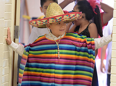 student looking from doorway while dressed in sombrero and serape