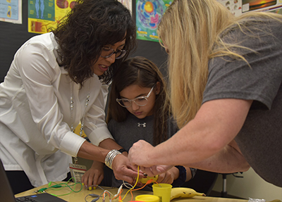 two teachers working on science project with student