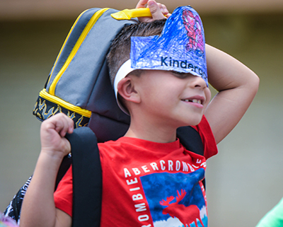 kid with lunchbox and hat over head