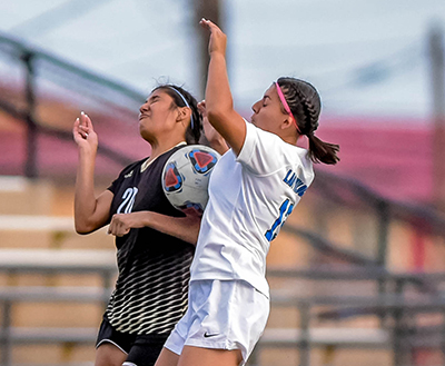 two girls with soccer ball between them