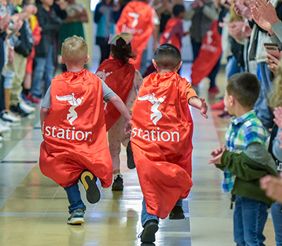 three kids in capes running down halls