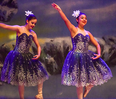 two girls on stage with arms in air