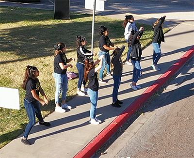 girls standing on side of street cheering