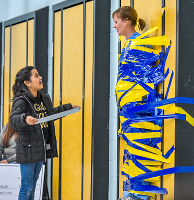 smiling girl and prinicpal taped to wall