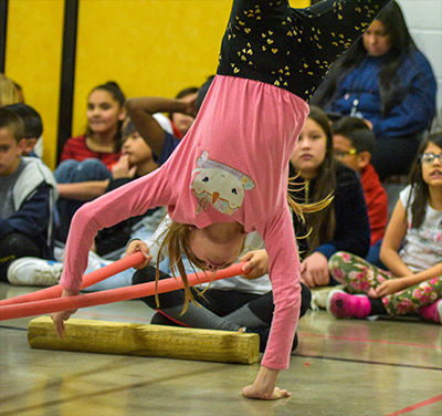 girl doing headstand between sticks