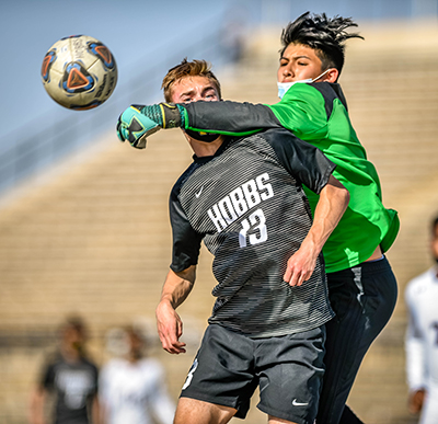 goalie punching ball away while opposing player watches