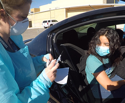 woman preparing to give shot to a person in car