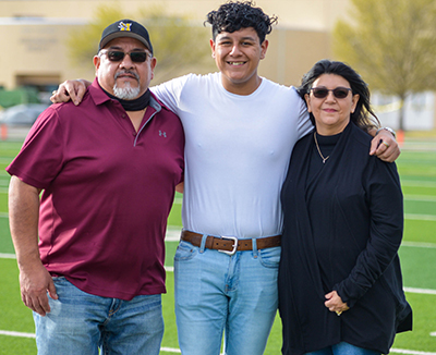 student standing with smiling parents