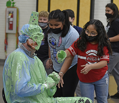 man sitting while kids dump green stuff on him