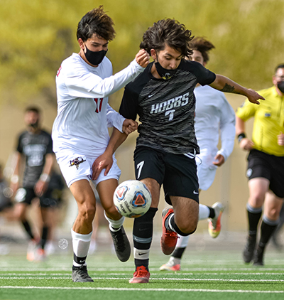 two opposing soccer plays battling for ball