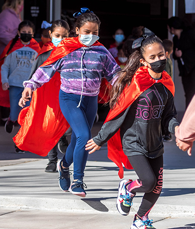 students in capes running outside