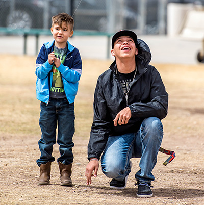 little boy flying kite next to teen