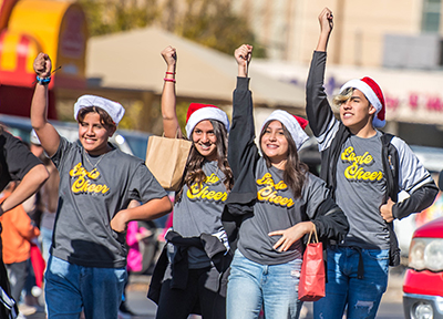 students in christmas hats marching down street