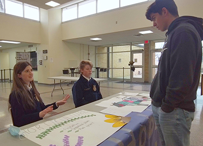 three students speaking at a desk