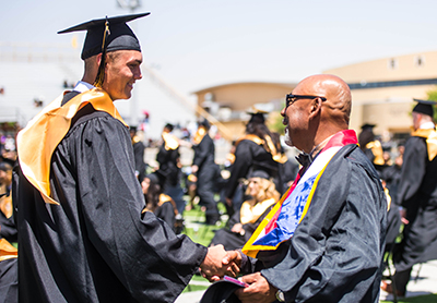 smiling grad shaking smling teacher's hand