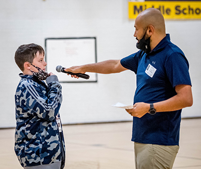 boy talking into microphone held by teacher