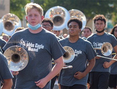 students marching with instruments under arms