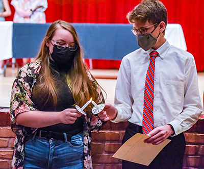 two students in masks lighting candles