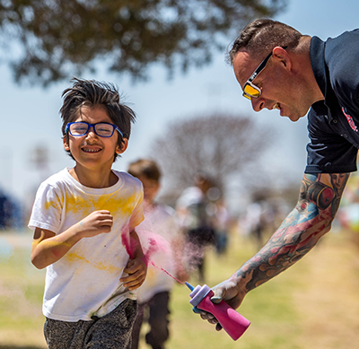 kid running while smiling man puts powder on him